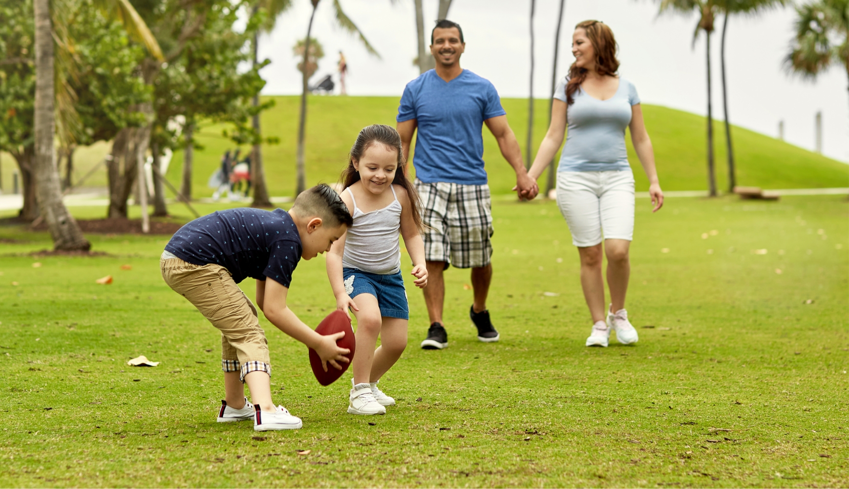 Family playing football on grassy field